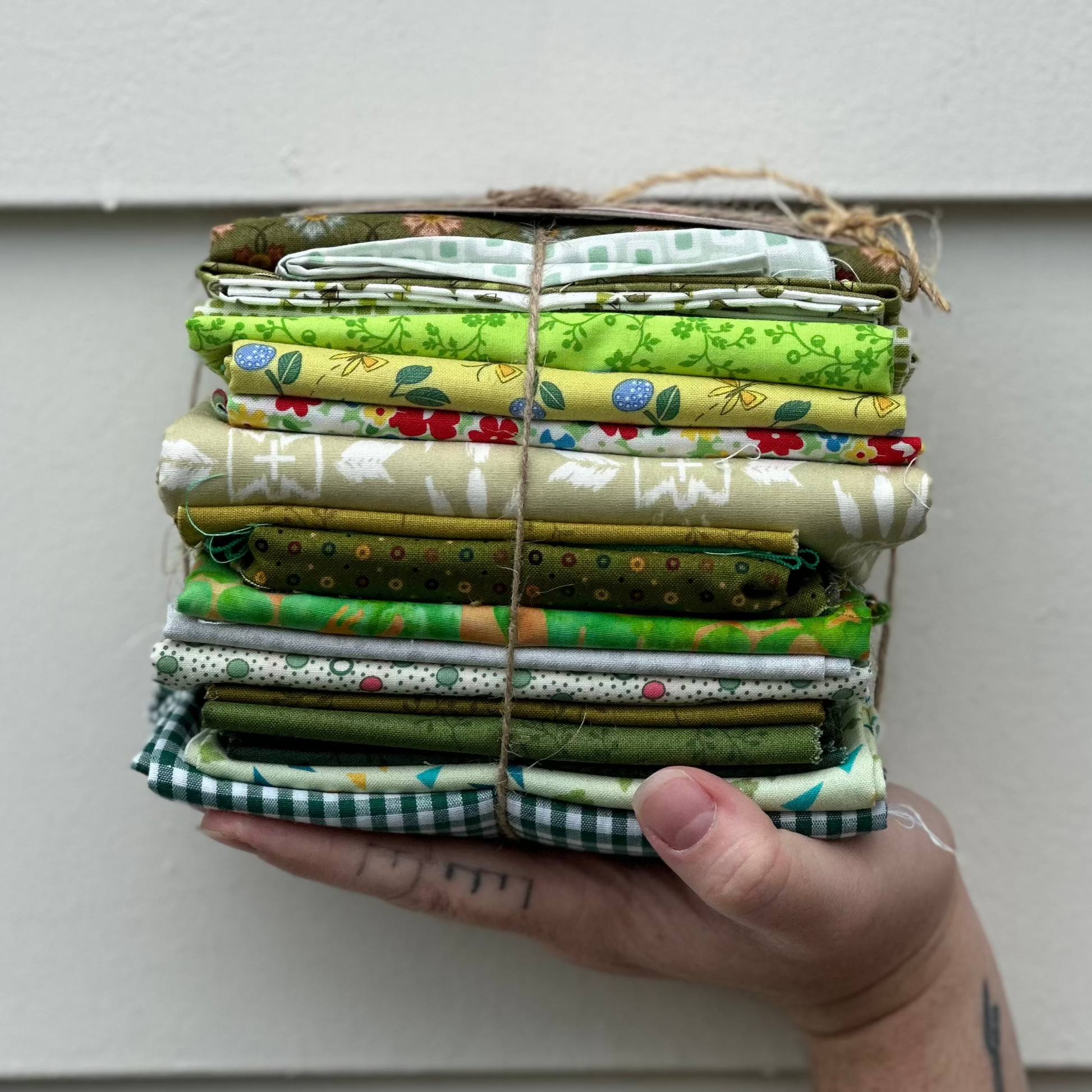 Stack of fabric bundles held by a hand against a white wall