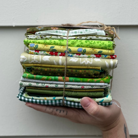 Stack of fabric bundles held by a hand against a white wall