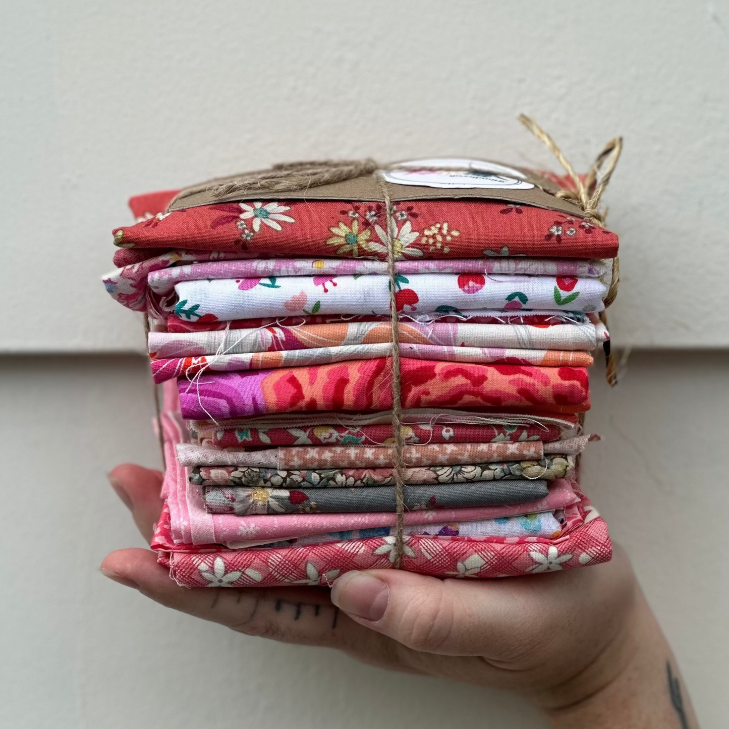 Hand holding a stack of colorful fabric bundles against a white background