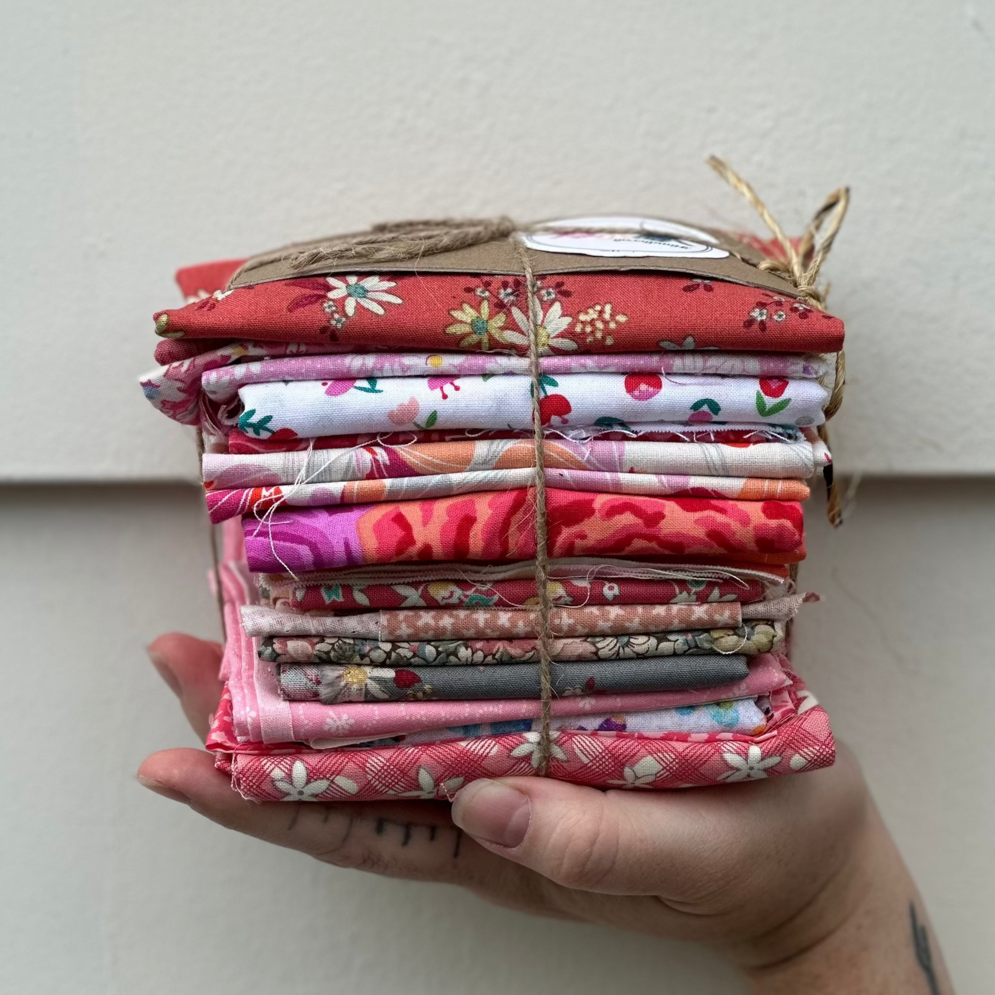 Hand holding a stack of colorful fabric bundles against a white background