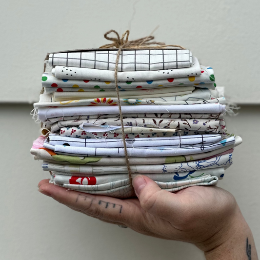 Hand holding a stack of folded fabric swatches against a neutral background